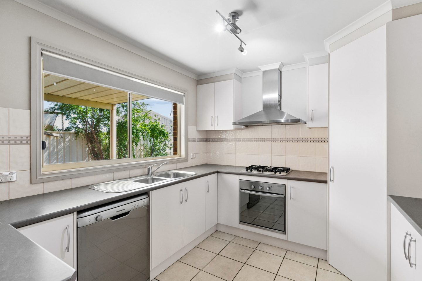Kitchen with gas cooktop, dishwasher, white cabinetry and a window over the sink