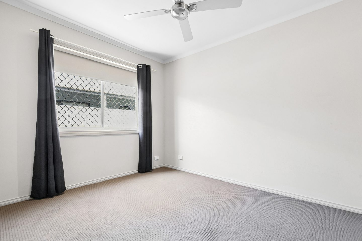 A carpeted bedroom with a ceiling fan