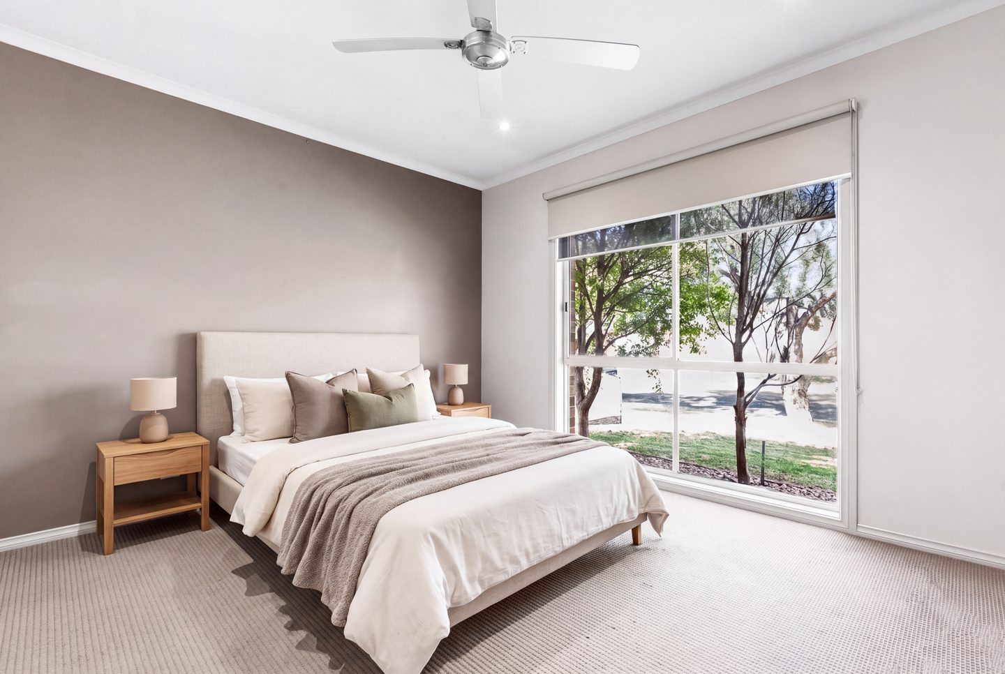 Main bedroom with a large front window and ceiling fan
