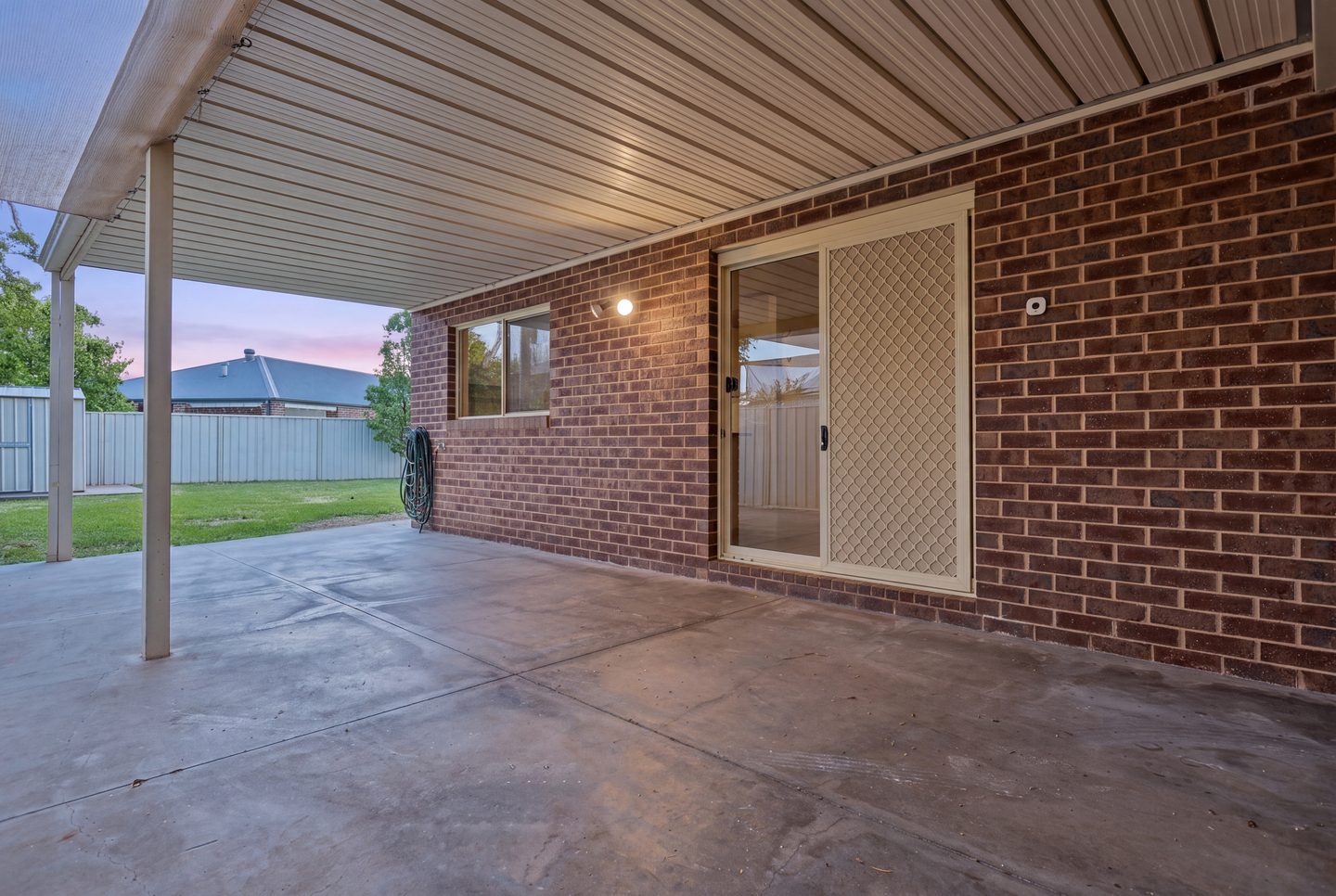 Covered patio and rear lawn at dusk